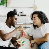Couple sharing food on the coach.